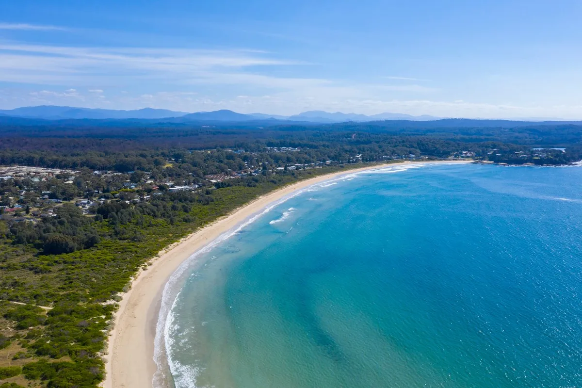 Aerial view of the coastline south of Jervis Bay, with the beach curving away below bushland